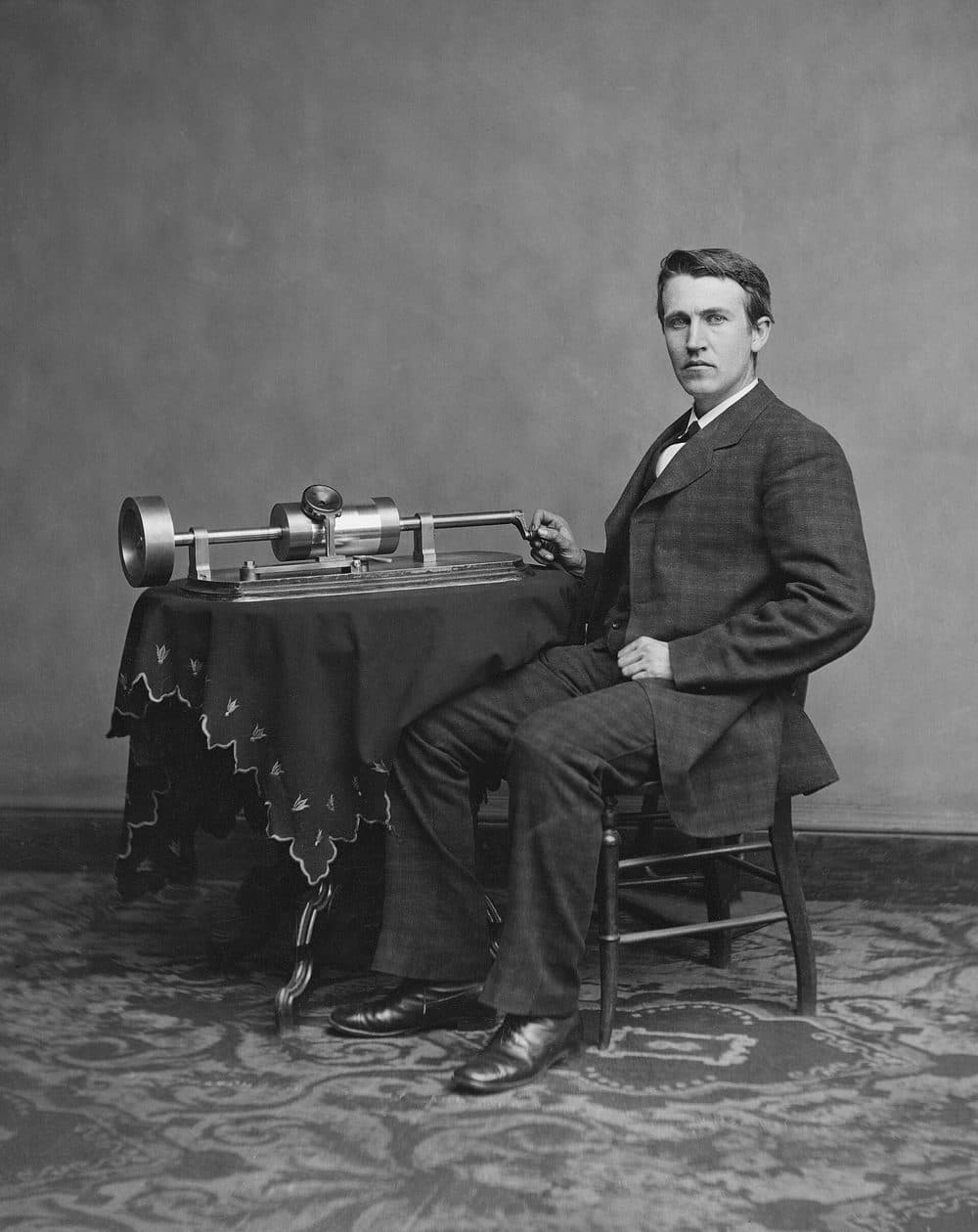 Photograph of Thomas Edison seated beside his tinfoil phonograph